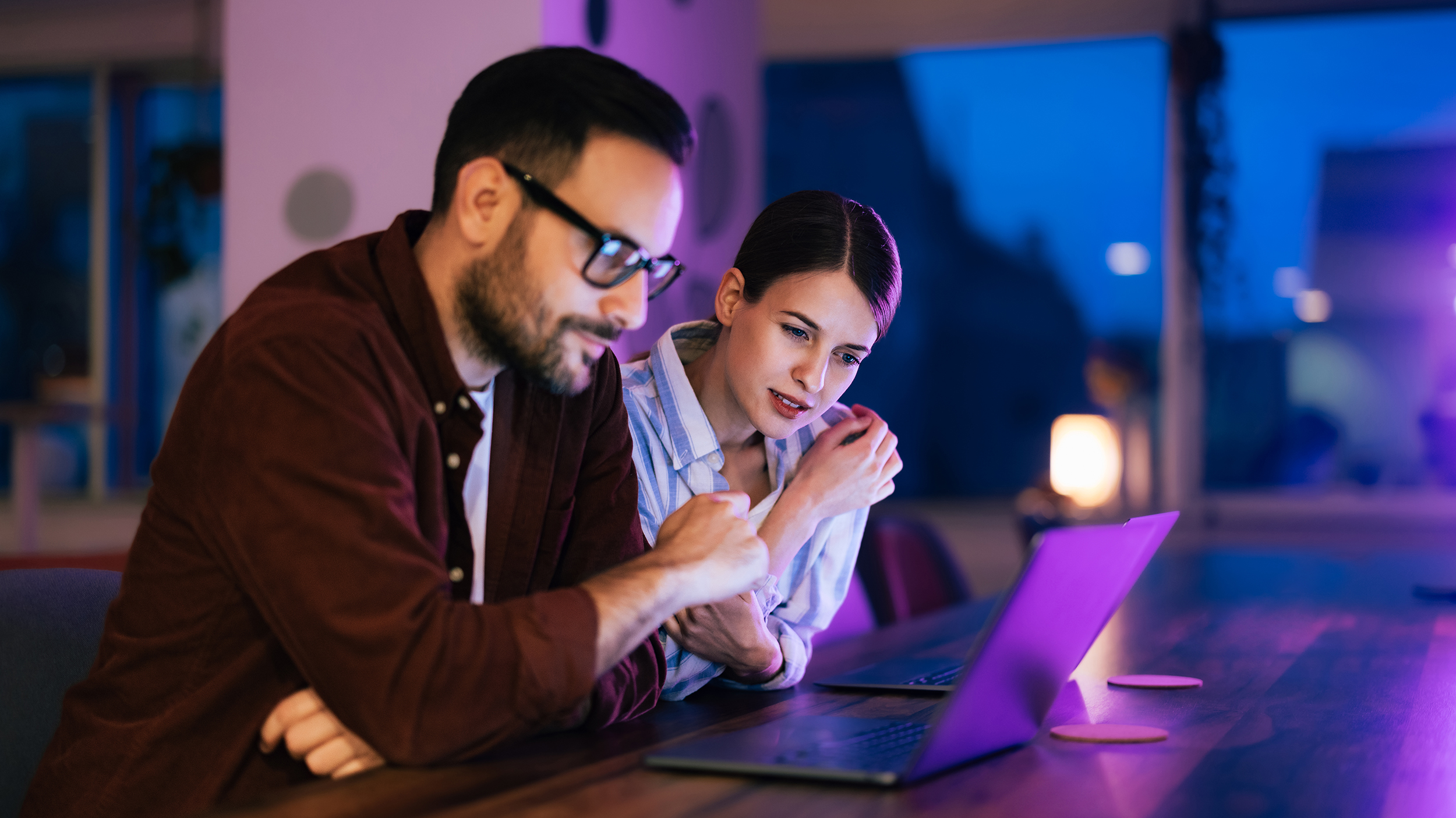 A male and female colleague working over the laptop sitting at the office